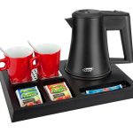 Black hospitality tray with black kettle and 2 red mugs with teaspoons inside them. The tray shows single use fruit tea and sugar sachets. Items not included unless specified - tray only