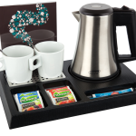 Hotel hospitality trays tea and coffee Black hospitality tray with silver kettle, 2 white mugs, spoons inside the mug. The tray shows single use fruit tea and sugar sachets. Items not included unless specified - tray only