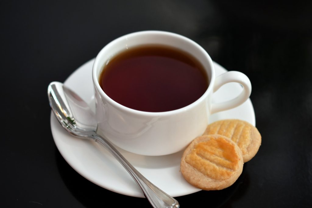 A white cup and saucer of hot tea and shortbread cookies for afternoon tea at a fancy hotel.