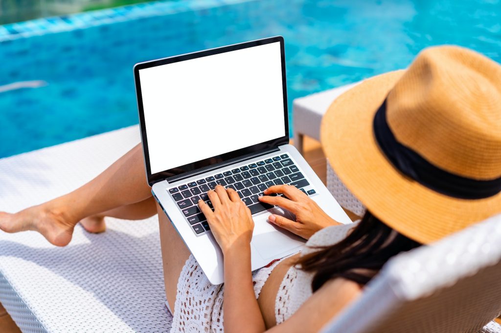 Young woman freelancer traveler working online using laptop while traveling on summer vacation